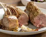 Costolette di agnello al forno succulente, condite con erbe aromatiche, servite su un piatto con verdure arrosto.