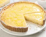 Una deliziosa crostata con crema pasticcera, guarnita con scorza di limone e spolverata di zucchero a velo.