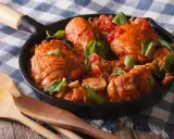 Pezzi di coniglio alla cacciatora in padella con pomodoro, olive e basilico, pronti per essere gustati.