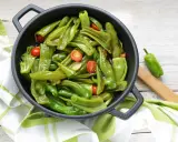 Friggitelli in padella, saltati con pomodorini e aglio, pronti per essere gustati.