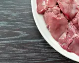 Piatto bianco con durelli di pollo crudi, pronti per essere cucinati.