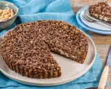 Sbriciolata ricotta e cioccolato con croccante copertura di nocciole. Una fetta è già servita su un piattino.