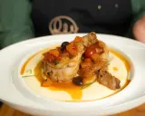 Pollo alla cacciatora ricetta della nonna: succulenti pezzi di pollo in umido con pomodoro, olive e carote, serviti su un letto di polenta cremosa.