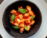 Gnocchi di ricotta soffici e saporiti, conditi con un sugo di pomodoro fresco e guarniti con foglie di basilico.