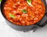 Pappa al pomodoro fumante in una pentola nera, guarnita con foglie di basilico fresco. Un classico piatto toscano.