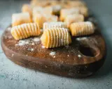 Gnocchi di patate fatti in casa, pronti per essere cucinati, spolverati di farina su un tagliere di legno.