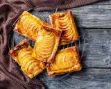 Deliziosi dolci con pasta sfoglia rettangolare, ripieni di mele caramellate, su una griglia di raffreddamento.