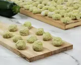 Gnocchi di zucchine freschi, pronti per essere cotti, disposti su taglieri di legno.