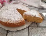Una soffice torta al latte, spolverata di zucchero a velo, con una fetta appena tagliata pronta per essere gustata.