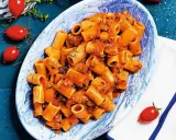 Rigatoni conditi con un sugo rosso saporito, ricco di tonno e erbe aromatiche. Un piatto di pasta al tonno invitante.