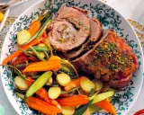 Un succulento agnello al forno, affettato e guarnito con erbe aromatiche, servito con patate novelle, carote e fagiolini.