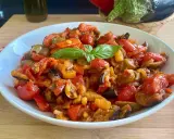 Caponata siciliana ricetta della nonna: melanzane, pomodori, peperoni e basilico in un piatto bianco.