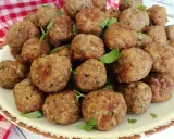 Un piatto colmo di polpette in bianco, dorate e profumate, guarnite con prezzemolo fresco.