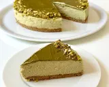 Una fetta di goloso cheesecake al pistacchio, con topping e granella di pistacchi, su un piatto bianco.