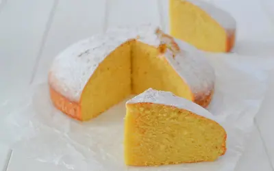 A fluffy lemon cake dusted with powdered sugar, with two slices cut out.