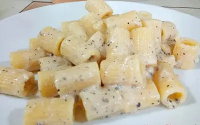 Piatto di rigatoni cremosi conditi con un classico cacio e pepe, pronti per essere gustati.