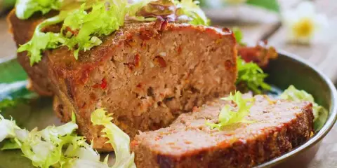 Un succulento polpettone al forno, tagliato a fette e guarnito con insalata fresca.