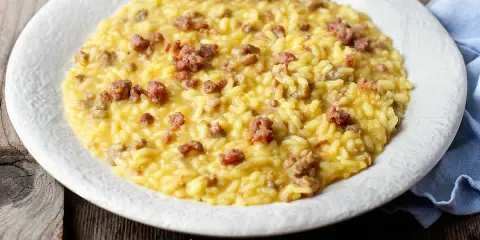 Un cremoso risotto con salsiccia, servito su un piatto bianco, pronto per essere gustato.