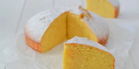 A fluffy lemon cake dusted with powdered sugar, with two slices cut out.