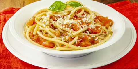 Un piatto invitante di pasta alla carrettiera, con pomodoro fresco, basilico e abbondante formaggio grattugiato.