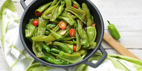Friggitelli in padella, saltati con pomodorini e aglio, pronti per essere gustati.