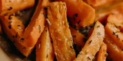 Carote in padella, tagliate a bastoncino e condite con erbe aromatiche, pronte per essere gustate.