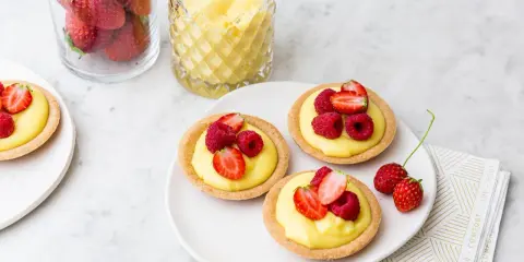 Deliziose tartellette alla frutta con crema pasticcera e frutti di bosco freschi, pronte per essere gustate.