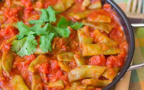 Taccole al pomodoro cotte in padella, guarnite con prezzemolo fresco. Un piatto semplice e gustoso.