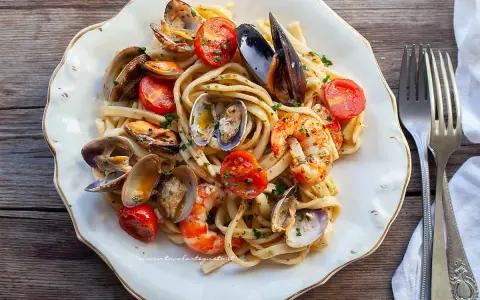 Un piatto invitante di scialatielli ai frutti di mare, con cozze, vongole, gamberi e pomodorini freschi, guarnito con prezzemolo.