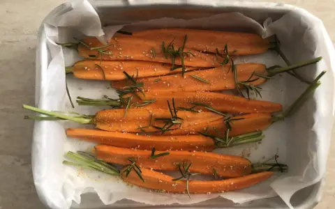 Carote al forno, condite con rosmarino e semi di sesamo, pronte per essere gustate.