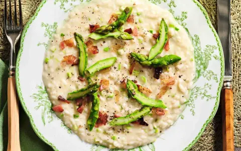 Un cremoso risotto asparagi e zafferano, guarnito con punte di asparagi freschi e cubetti croccanti di pancetta.