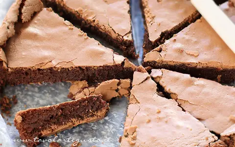 Una deliziosa torta al cioccolato, tagliata a fette triangolari, mostra la sua consistenza umida e ricca.