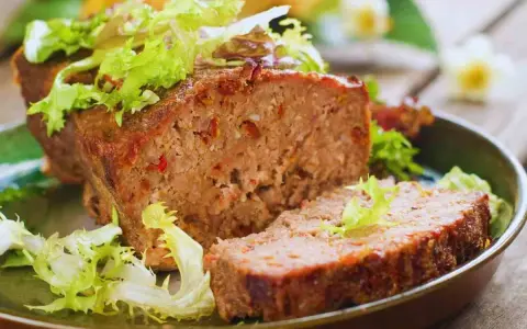 Un succulento polpettone al forno, tagliato a fette e guarnito con insalata fresca.