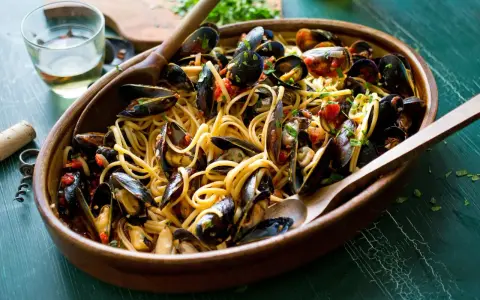 Un invitante piatto di spaghetti con le cozze, condito con pomodoro e prezzemolo, pronto per essere gustato.