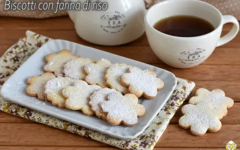 Biscotti con farina di riso a forma di fiore, spolverati di zucchero a velo, serviti con una tazza di tè.