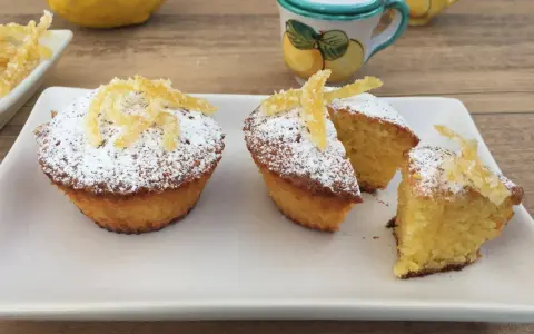Deliziosi muffin caprese al limone, spolverati di zucchero a velo e decorati con scorzette candite.