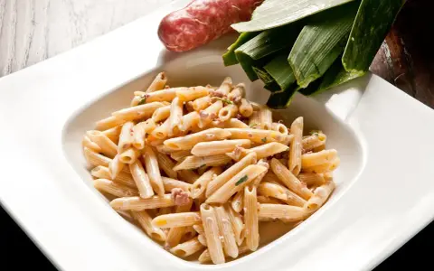 Penne cremose con salsiccia e verdure, un piatto di pasta alla norcina che invita alla tavola.