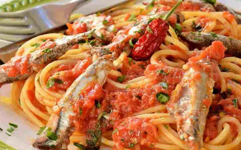Spaghetti con sugo di pomodoro, acciughe intere e un peperoncino rosso piccante. Un piatto di pasta semplice e saporito.