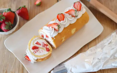 Rotolo panna e fragole decorato con panna montata e fragole fresche, pronto per essere gustato.