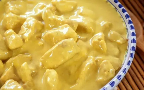 Un invitante pollo al curry con latte di cocco, cremoso e profumato, servito in una ciotola decorata.