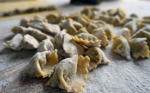 Un mucchio di ravioli del plin freschi, spolverati di farina, pronti per essere cucinati.