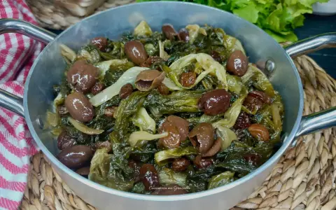 Scarola in padella con olive e uvetta, un contorno saporito e colorato, pronto per essere gustato.