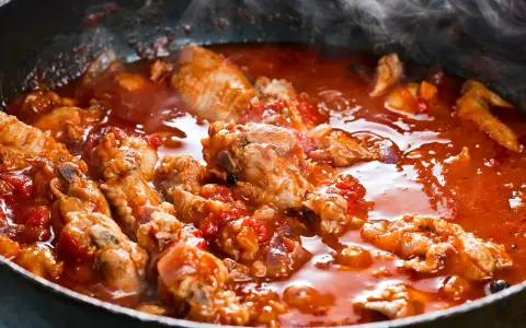 Succulenta carne alla pizzaiola che sobbolle in padella, sprigionando un profumo invitante. Pezzi di carne tenera immersi in un sugo rosso ricco di pomodoro e spezie.