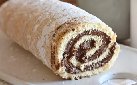 Un soffice rotolo alla Nutella, cosparso di zucchero a velo, pronto per essere gustato.