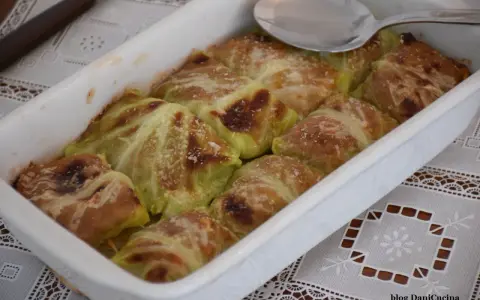 Involtini di verza con carne appena sfornati, dorati e spolverati di parmigiano, pronti per essere gustati.