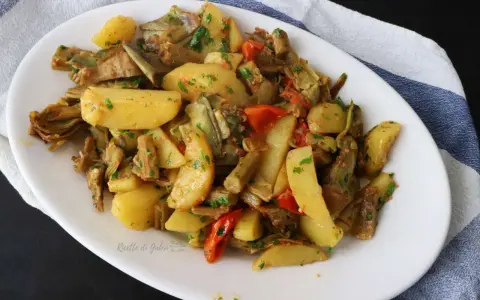 Deliziosi carciofi e patate in padella, un contorno saporito e colorato, arricchito da pomodorini e prezzemolo fresco.
