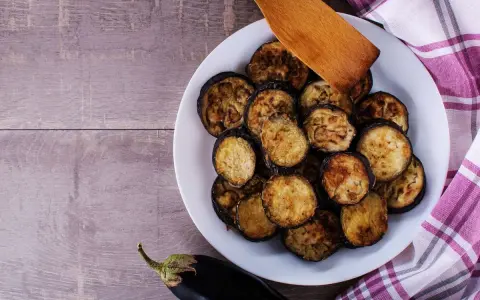 Fette di melanzane grigliate in friggitrice ad aria, dorate e pronte per essere gustate.