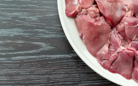 Piatto bianco con durelli di pollo crudi, pronti per essere cucinati.