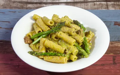 Piatto di pasta con asparagi e salsiccia, condita con una cremosa salsa verde.