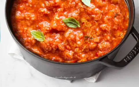 Pappa al pomodoro fumante in una pentola nera, guarnita con foglie di basilico fresco. Un classico piatto toscano.
